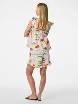 Short de tiro alto con cintura elástica y detalles de volantes, confeccionado en tejido plano de mezcla de lino, algodón y viscosa. Presenta un diseño holgado con estampado multicolor de limones, frutillas y texto sobre fondo rosado.