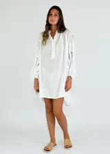 Vestido corto blanco con mangas largas con detalles de encaje, cuello mao y cierre parcial con botones.