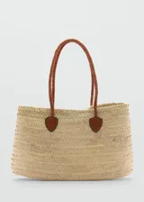 Bolso tipo tote de paja color beige con asas de cuero trenzado color marrón.