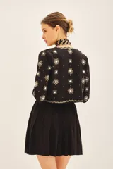 Saco corto negro, ajustado al cuerpo, con escote redondo y bordado a mano en frente, espalda y mangas con lentejuelas y pedrería en forma de estrellas y motivos florales.
