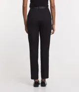 Pantalón de vestir negro de corte carrot, con cintura alta, trabillas y cinturón con hebilla metálica.