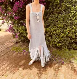 Vestido corto tejido en lurex con diseño geométrico en cuero en el frente, breteles de cuero intervenido a mano con tientos de cuero plateado y terminación en flecos.