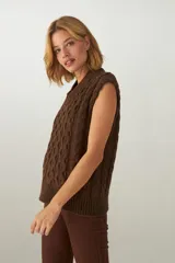 Chaleco de punto color crema con diseño trenzado y cuello en V.