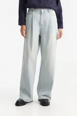 Jean largo de tiro medio y corte amplio, color celeste claro con efecto lavado, con pinzas delanteras y terminación de ruedo desflecada.