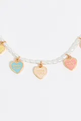 Pulsera de perlas con charms dorados en forma de corazón con detalles de esmalte de colores y logo grabado.