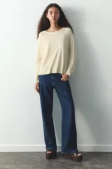 Jersey de punto color verde oliva, con cuello redondo y manga larga. Tiene bajo con aberturas laterales y acabados en rib.