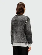 Buzo de tejido grueso con efecto jaspeado o acid wash en tonos de gris y negro. Presenta cuello redondo, puños y ruedo en tejido acanalado gris claro. Tiene un detalle de costura blanca en la sisa.