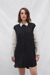 Vestido camisero corto negro con mangas largas color crema, cuello camisero blanco y cierre frontal con botones.
