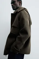 Parka verde oscuro confeccionada en tejido con lana, corte regular, cuello solapa con capucha desmontable, manga larga con puño ajustable, bolsillos de vivo en cadera y cierre frontal con cremallera oculta por solapa con botones a presión.