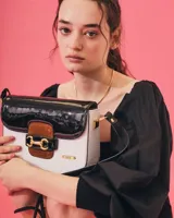 Bandolera color beige con textura símil reptil, cierre con broche metálico dorado y correa larga regulable.