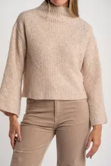 Polera de tejido de punto color beige jaspeado, con cuello alto y mangas largas acampanadas. Diseño de calce oversize.