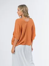 Remerón tipo poncho color naranja confeccionado en lino italiano, con escote en V y bolsillos laterales.
