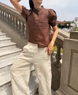 Camisa color ladrillo confeccionada en lino, con cuello mao, mangas cortas abullonadas y cierre frontal con botones.