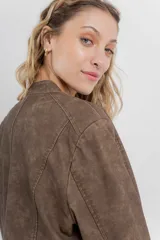 Chaqueta tipo biker de cuero ecológico (PU) color marrón con acabado desgastado, cuello Mao con broches metálicos, cierre frontal y bolsillos con cremallera.
