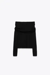 Top de punto negro con escote recto, hombros descubiertos, mangas largas y detalle de pieza metálica plateada en el delantero.