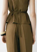 Pantalón de tiro medio color marrón, con trabillas, cierre delantero con cremallera y botón, dos bolsillos laterales, pinzas delanteras y diseño recto con aberturas en el bajo.