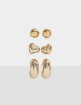 Set de tres pares de aros dorados con diferentes diseños: un par de aros tipo botón, un par con forma de corazón y un par de argollas gruesas.