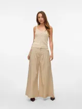 Pantalón oversize de pierna ancha color beige, con pliegues y bolsillos laterales.