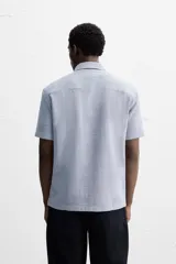 Camisa celeste de corte recto, manga corta y cuello solapa.