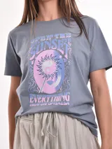 Remera color amarillo claro con estampado frontal de la frase "Optimism is a lifestyle" en color lila.
