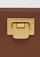 Bolso tipo bucket negro de poliuretano con asa corta y cierre metálico dorado.
