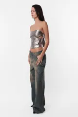Corset strapless plateado de cuerina PU con cinto en la espalda con hebilla y ojalillos metálicos para ajuste y cierre metálico para acceso a la prenda. Detalle de recortes en delantero y espalda que simulan ballenas.
