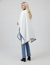 Ruana negra de tejido suave, con borde ribeteado en eco cuero y cierre frontal con botones metálicos dorados.