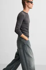 Pantalón de jean negro de corte amplio, con cinco bolsillos, efecto lavado y cierre frontal con cremallera y botón.
