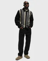 Cárdigan de punto con cuello polo, manga larga negra y cuerpo a rayas verticales en tonos negro, gris y beige. Presenta un pequeño bordado en el pecho.