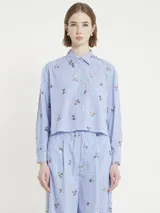 Camisa corta estilo boxy de cuadrillé celeste y blanco con bordado de flores, botones y canesú en la espalda.