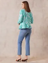 Campera blanca con bordado floral en verde agua, cuello solapa, cierre con botones, bolsillos delanteros y ruedo fruncido.