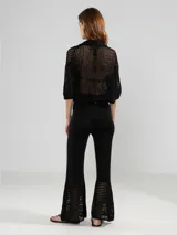 Camisa corta de punto abierto color negro, con cuello polo, mangas 3/4 y cierre frontal con botones.