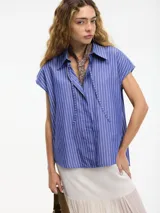 Camisa musculosa a rayas verticales azules y blancas, con cuello camisero, botones en la parte delantera y trasera, y lazo regulable en el cuello.