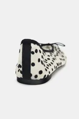 Zapato tipo bailarina con capellada de mesh color blanco y lunares negros. Tiene detalle de lazo negro en la puntera, tirador trasero y suela plana.