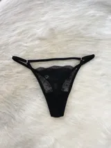 Conjunto de lencería negro de encaje elastizado, compuesto por un corpiño triangular, una tanga regulable y un portaligas con ligas incluidas.