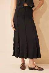 Falda larga negra de tela de punto arrugada con paneles verticales.