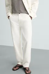 Pantalón de jean color blanco, corte recto, con bolsillos frontales y traseros, y cierre frontal con cremallera y botón.