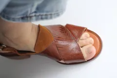 Sandalias de cuero marrón con tiras cruzadas en el empeine y tira alrededor del tobillo.