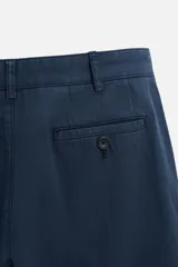 Pantalón azul marino de algodón con corte regular fit, bolsillos delanteros y traseros de vivo, cierre frontal con cremallera y botón.