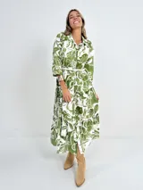 Vestido camisero midi de algodón con estampado floral en tonos verdes y blancos, manga 3/4, botones al frente, falda escalonada y cinturón de soga incluido.