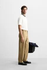 Pantalón chino color beige de corte recto, con cintura ajustable con cordón interior y trabillas laterales. Tiene bolsillos frontales y traseros de vivo.