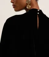 Blusa boxy de terciopelo negro con cuello alto y mangas cortas amplias.