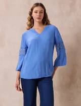Blusa celeste de gasa bambula con cuello a la base y escote en V. Manga ¾ amplia, con aplique de crochet en los puños.