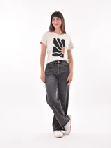 Remera negra de algodón con estampado frontal de la palabra "MERCI" en letras delineadas con colores del arcoíris.