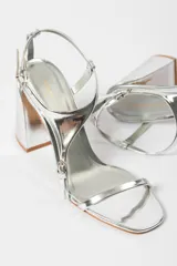 Sandalias plateadas de tacón bloque con tiras finas y cierre con hebilla en el tobillo.