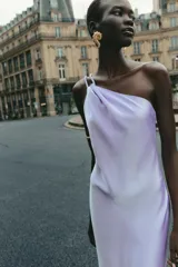 Vestido midi de satén color lila, con escote asimétrico y tirantes finos. Cierre lateral con cremallera oculta.