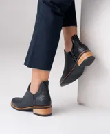 Botín de cuero negro con textura de rejilla y tacón bajo.