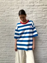 Remerón blanco con rayas horizontales azules, cuello redondo y ribete rojo. Presenta un pequeño bordado en el pecho.