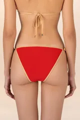 Calzón de bikini rojo con ribetes dorados y diseño de tiritas laterales.