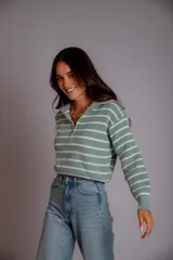 Sweater de punto color beige con rayas horizontales blancas, cuello polo con cierre de cremallera y mangas largas.